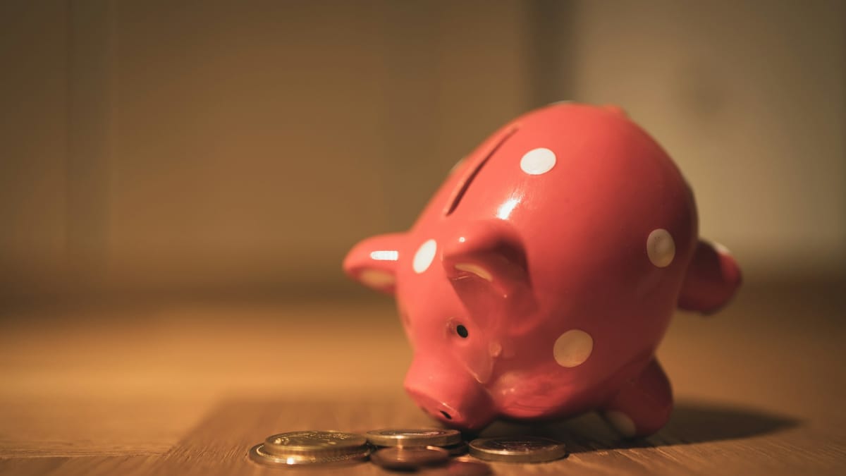 A pink piggy bank on a wooden table, representing money diverted into pension savings