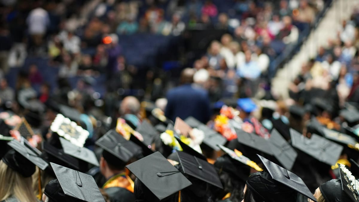 A large group of graduates in caps and gowns at a university graduation ceremony